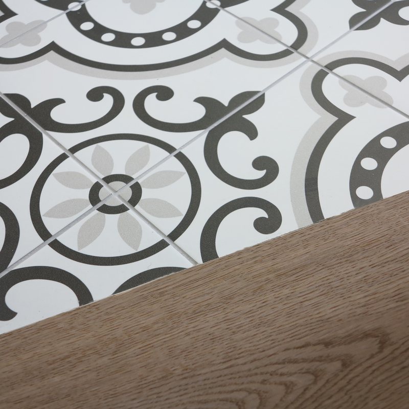Détail de sol : ligne de partage entre carreaux de ciment et parquet en chêne