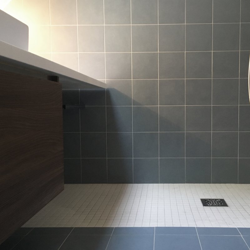 Salle de bains carrelée : douche de plain-pied et meuble suspendu en noyer