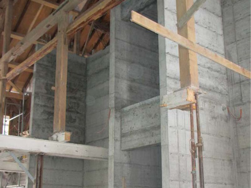 Chantier de Bourdigny-Dessus : noyaux et gaine d'ascenseur en béton insérés sous la charpente existante de la grange